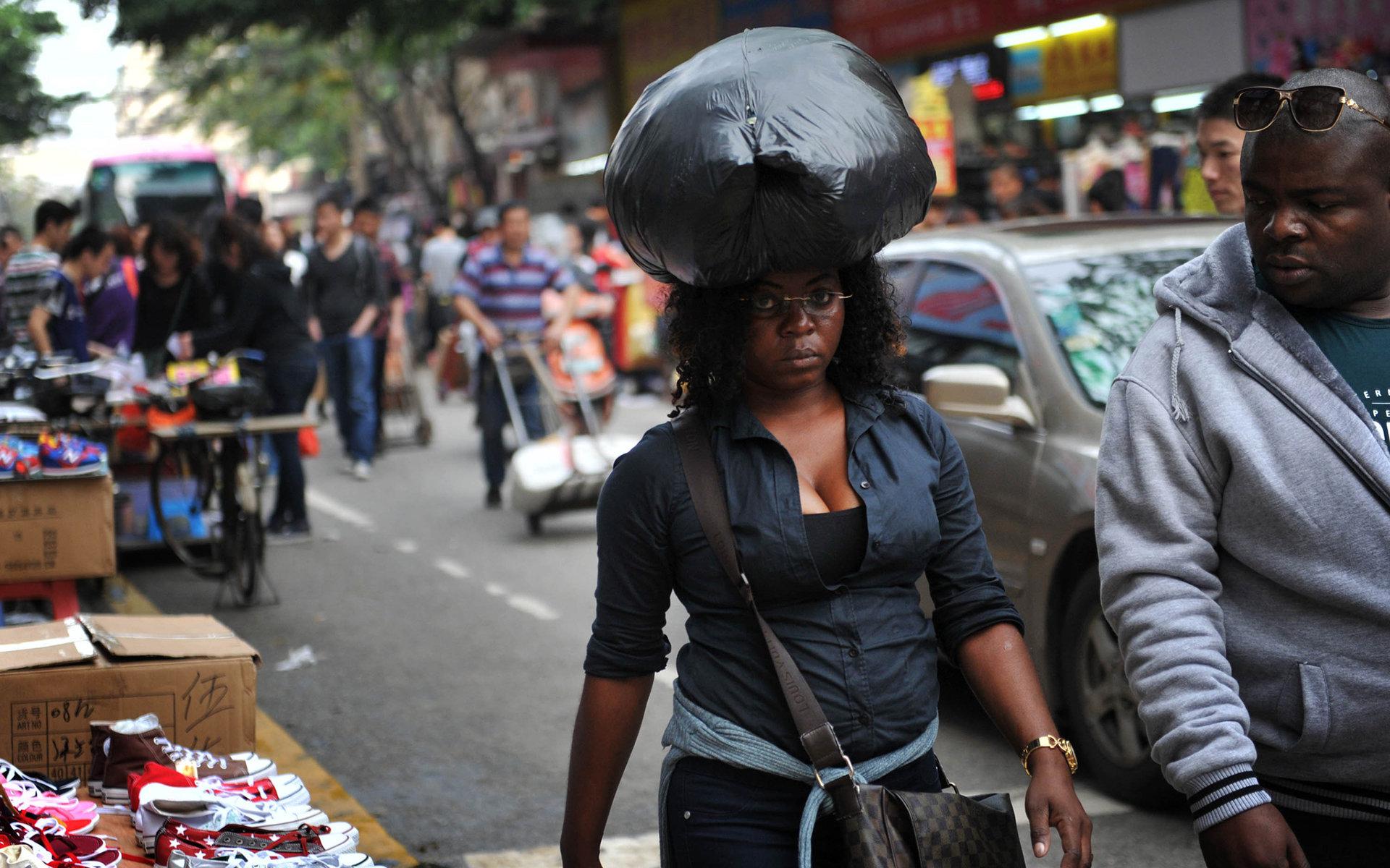 2014年4月3日，广州市一名黑人女子头顶刚挑选好的货品。/视觉中国