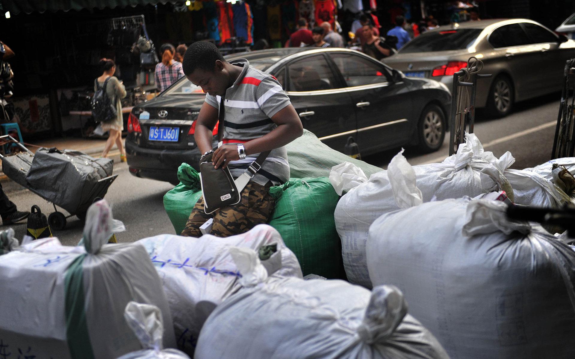 2014年4月3日，广州市一服装城旁一名拿到货的黑人男子在清点货品。/视觉中国