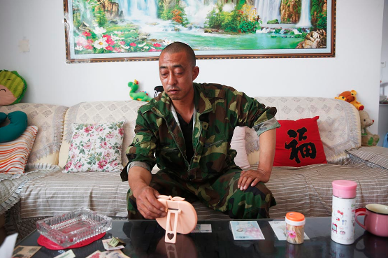 消防员杨伟光的父亲杨杰在一家人租住的平房里。摄：Howard/端传媒