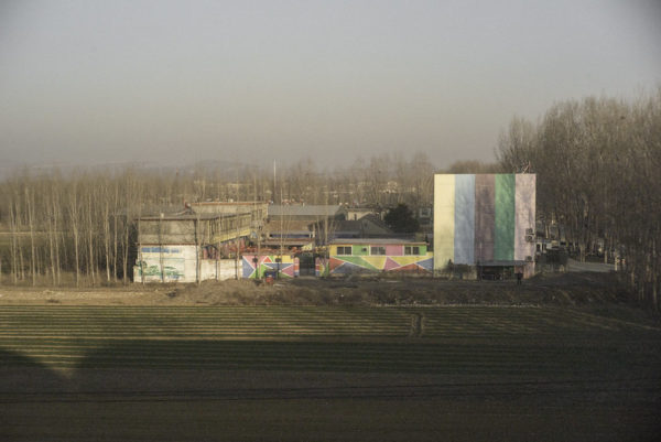 Brightly painted buildings stand out against muted, dust-colored surroundings