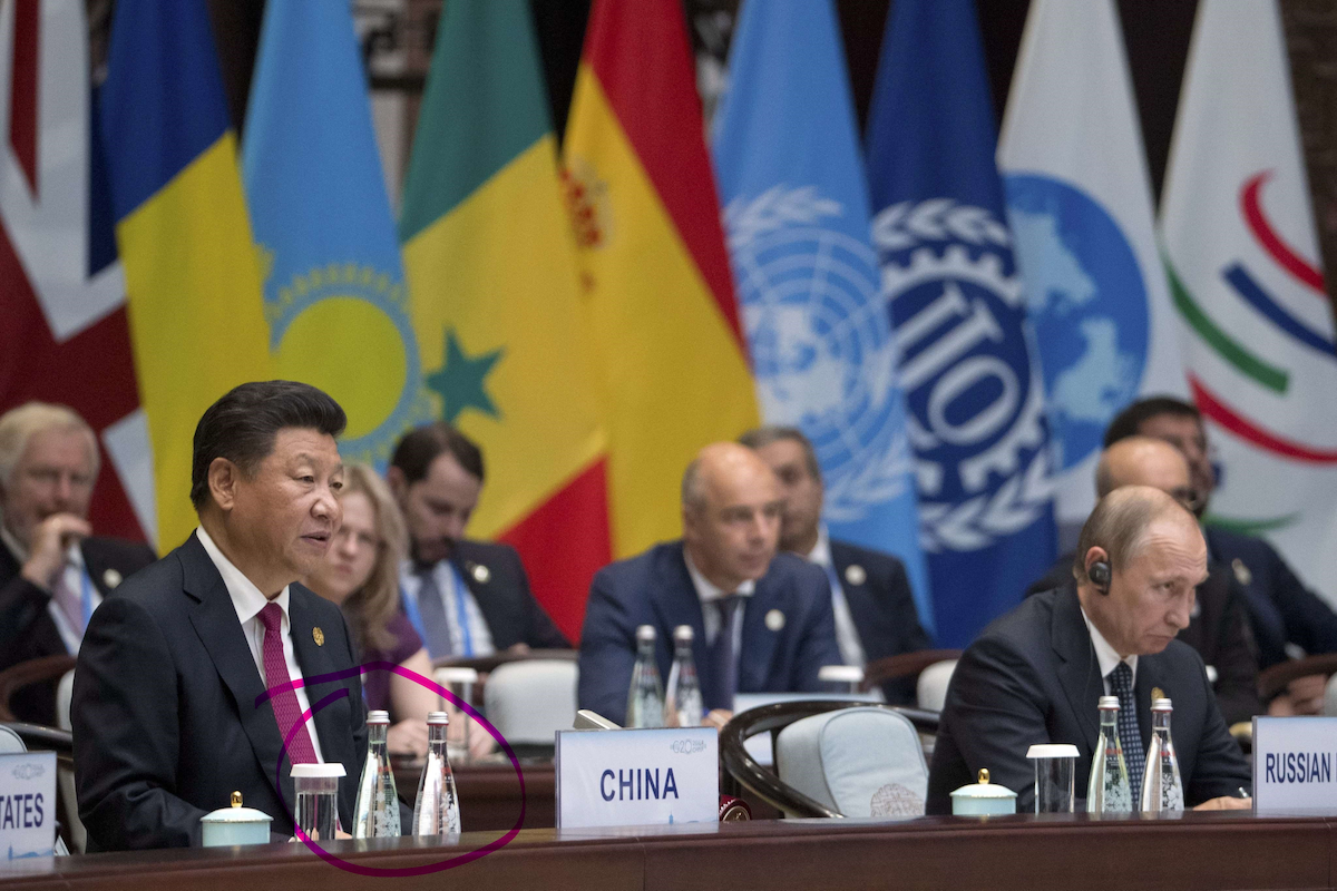 Xi Jinping sits at a desk in what appears to be a United Nations meeting with other national leaders (including Vladimir Putin, at right). There are two bottles of pricey, high-end Nongfu Spring Water on the desk in front of Xi Jinping.