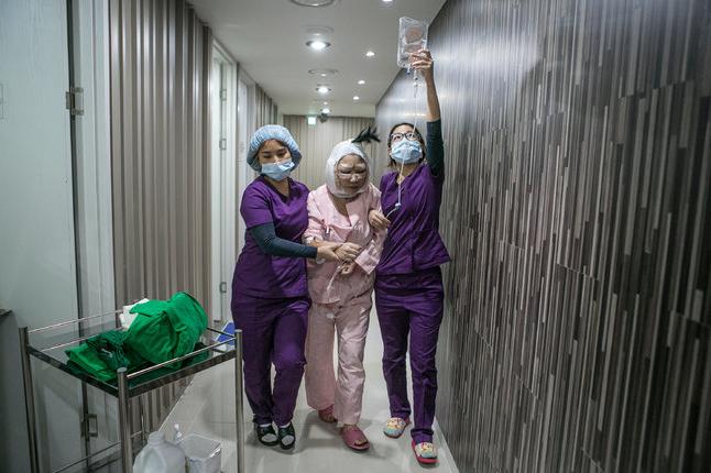 卢淑娟（音）在奥拉克诊所护士们的帮助下走向康复室。韩国正在成为中国医疗整形游的热门目的地。
