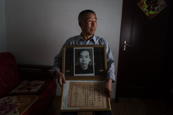 陈书祥手捧祖父的照片及他曾在一所大学工作过的证明文件。他将此视若珍宝，因为他在文革中遇害的父亲没有留下一张照片。