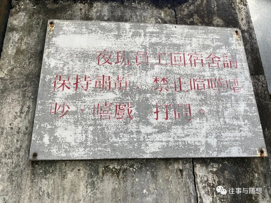 A weathered grey and white sign with faded red Chinese characters