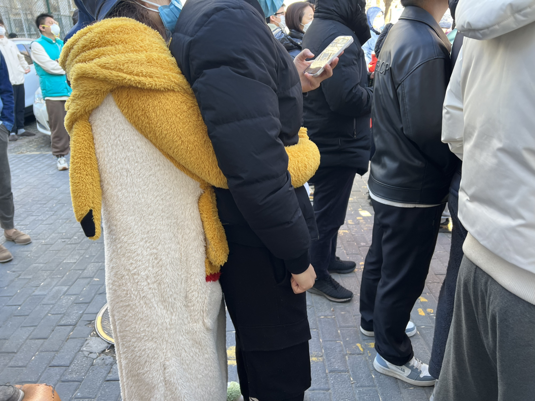 A woman in white-and-yellow fuzzy “onesie” pajamas embraces a man in a puffy black jacket.
