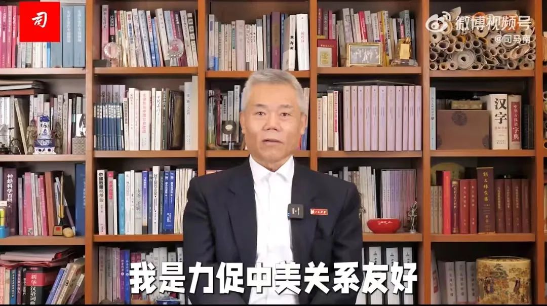 A screen-grab of a TV program featuring Sima Nan, wearing a dark suit jacket and white shirt, sitting in front of a wall of books in bookcases. 