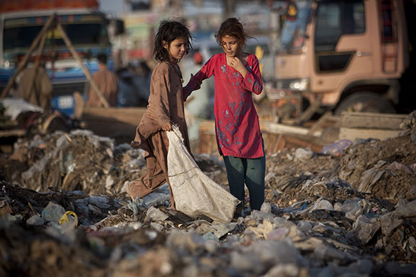 24 Hours in Pictures: Two Afghan refugee children look for recyclable items at a rubbish site
