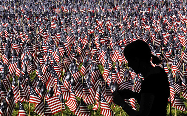 24 Hours in Pictures: A woman walks by a sea of flags planted in memory of fallen U.S. servicemen