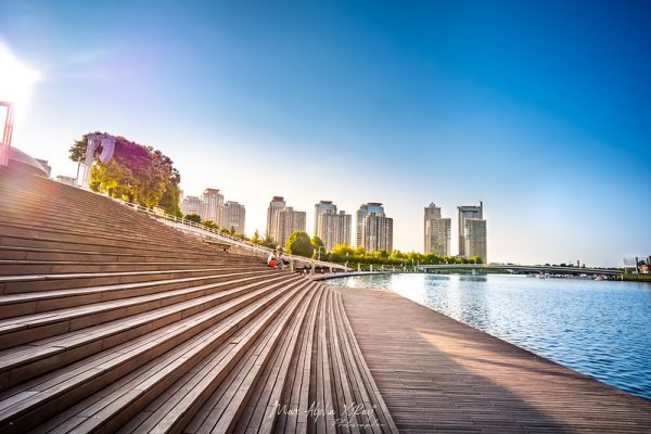 A wooden boardwalk runs beside a shimmering blue river, and low wooden steps rise toward the Henan Arts Centre in Zhengzhou, the capital city of Henan. Uruguayan architect Carlos Ott said that the Arts Centre’s architecture was inspired by ancient Chinese wind instruments.