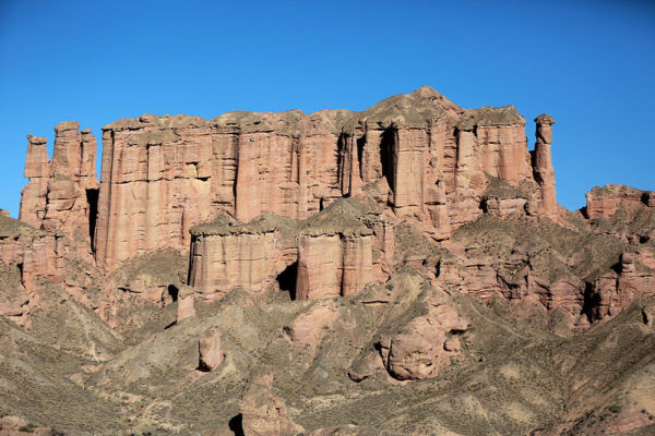 An outcropping of sculpted-looking sandstone pillars tower like a natural cathedral against a vivid blue sky.
