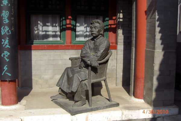 Against the gray brick walls and green and vermillion windowsills and pillars of the Lu Song Yuan Hotel in Beijing, is a seated statue of famed writer, essayist, and poet Lu Xun (1881-1936), known as the father of modern Chinese vernacular literature.