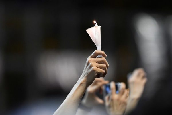 A hand holds up a candle encased by a paper cup. Taken at a June 4th, 2019 mass candlelight vigil in Hong Kong to mark the 30th anniversary of the violent Tiananmen crackdown and to honor the protesters who died.