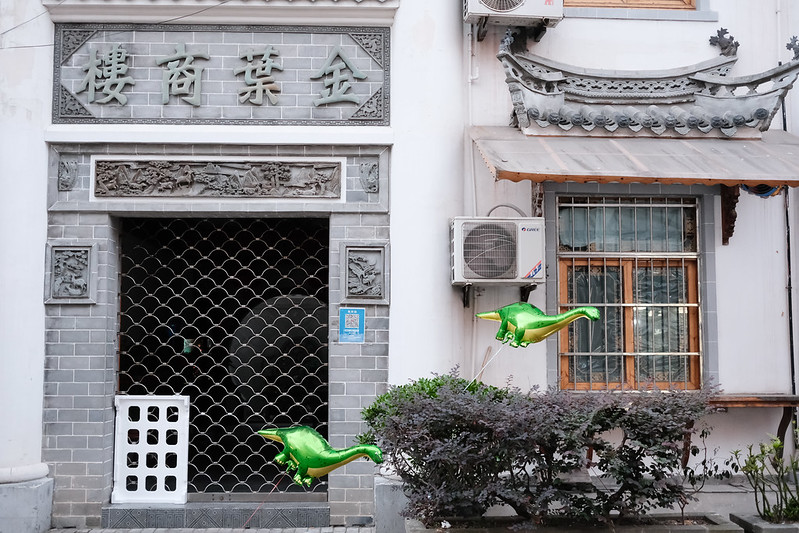 Dinosaur balloons float in front of a building in Shanghai