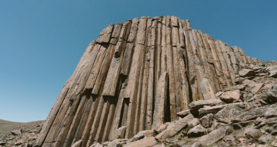 Against a bright blue sky, the majestic volcanic rock pillars of Shitiao Mountain in Inner Mongolia, China, tower like an enormous pipe organ constructed out of basalt.