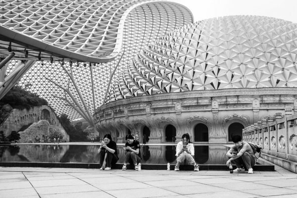Against the spectacular geometrically patterned dome of Nanjing’s Usnisa Palace, four young people sit or squat as they stare in rapt attention at their mobile phones.