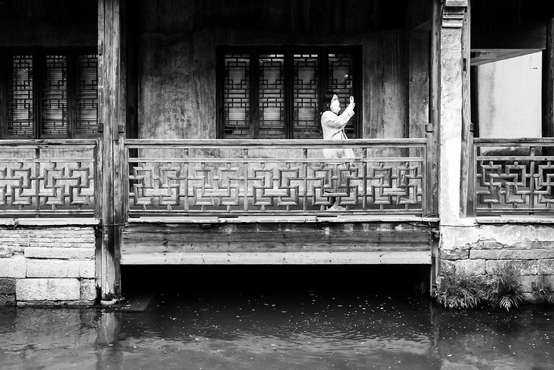 A woman takes a selfie under the eaves of a tradition-style Chinese building