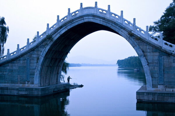 Soft blue and purple hues add a peaceful air to this portrait of a lone man fishing in a placid lake beneath the enormous moon-shaped stone arch of an 18th-century pedestrian bridge at Beijing’s Summer Palace.