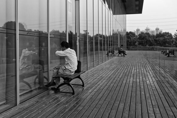Against the clean, modern, architectural lines of the Pudong Library in Shanghai, readers sit outside on benches, immersed in their books.