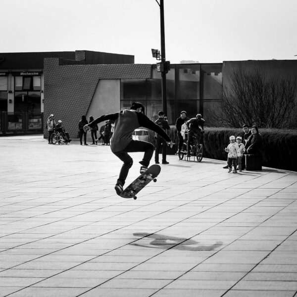 Showcasing his skills, a young skateboarder catches some air in Dalian’s Xinghai Square as several groups of people, including some little kids, look on in fascination.