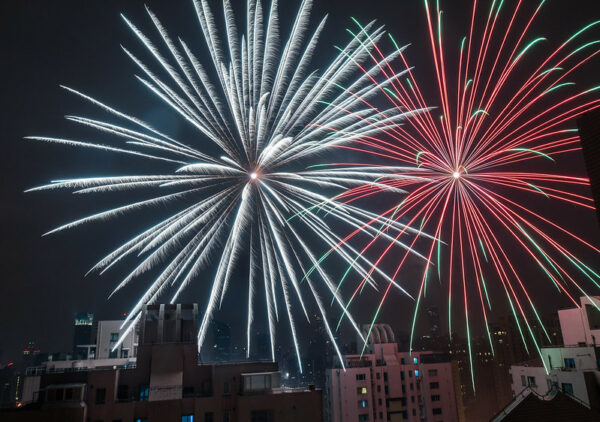 Two enormous “starburst-style” fireworks, one red and one white, fill the night sky above Shanghai’s skyline.