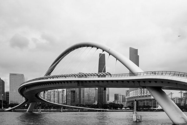 Guangzhou’s sleek modern Haixin Bridge curves gracefully over the water, against a backdrop of towering skyscrapers.