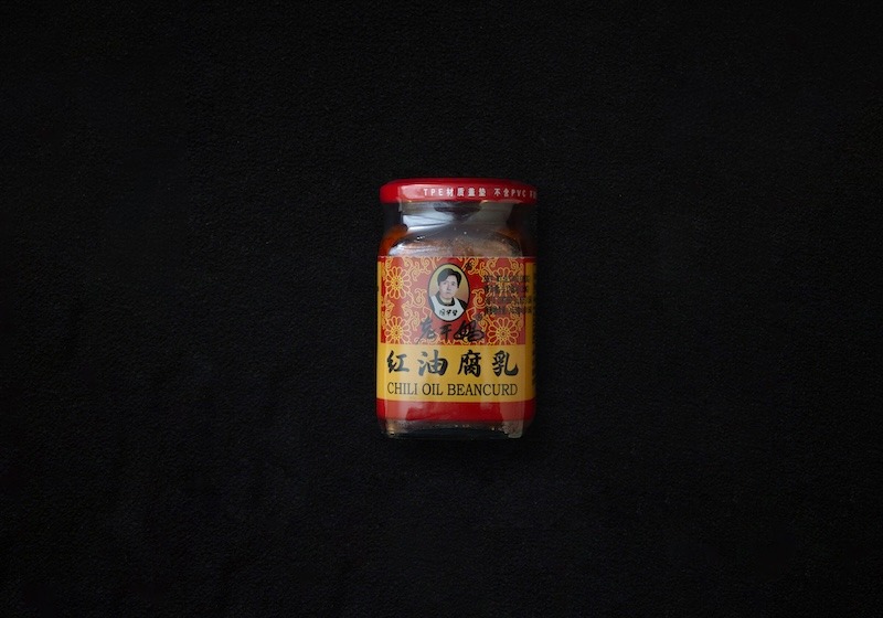 A red, yellow, and black glass jar of Laoganma's iconic spicy beancurd