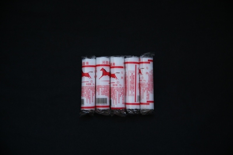 Five cylindrical red and white packages of moisturizing balm are adorned with red horses in the logo.