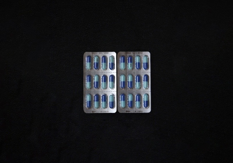 Two packets of pain reliever, each containing 12 light- and dark-blue capsules.