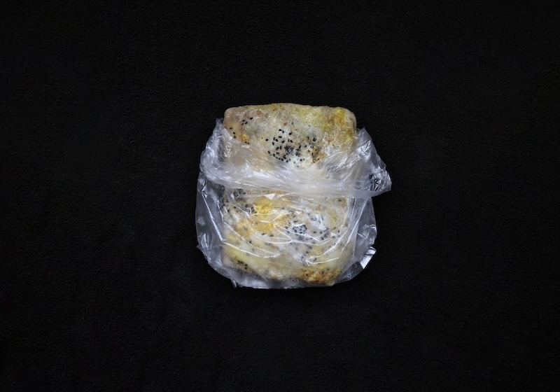 A crepe made with eggs and garnished with black sesame seeds in a plastic baggie